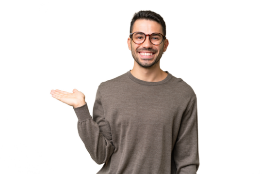 Young handsome caucasian man over isolated background holding copyspace imaginary on the palm to insert an ad