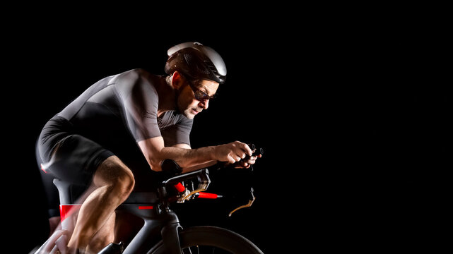 Cyclist sitting on turbo trainer against black background
