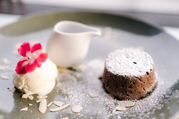 Chocolate fondant with scoop of ice cream, blackberry syrup and slices of almond 