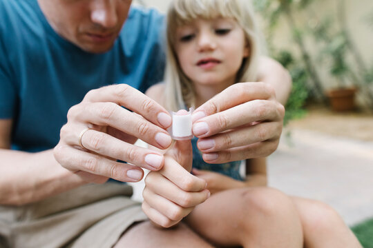 Father applying bandage on daughters thumb