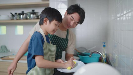 Asian father teaching son to wash dishes in the kitchen at home. Single father concept