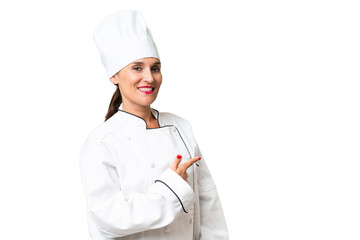 Middle-aged chef woman over isolated background pointing back