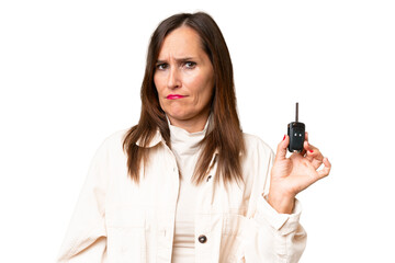 Middle-aged woman holding car keys over isolated background with sad expression