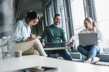 Happy business colleagues with solar panel in meeting at office