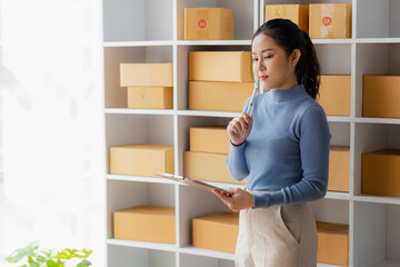 Startup, small business, SME, Asian female entrepreneur owner uses smartphones to talk to customers online and check online orders to prepare packages. Sell Ideas Online.