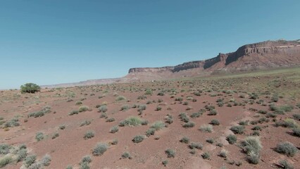 Experience an exhilarating FPV aerial journey over the vast Indian Creek desert, towards of cliffs in the distance on a sunny day.