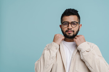 Young indian guy posing isolated over blue background