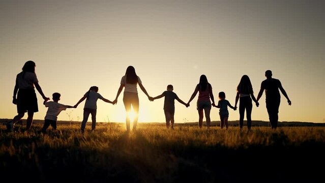 Big happy family. Group of people have fun walking in the park on green grass. Parents and children walk together holding hands at sunset. Family love and support. Family teamwork in park on vacation
