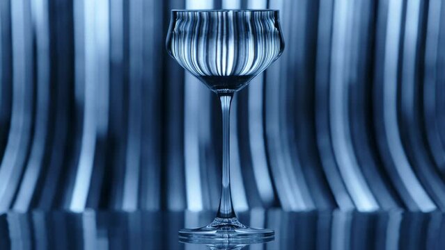 Clear wine glass standing infront of a fast falling rain like pattern in the background. The effect is reflected in the wine glass. High quality 4k footage