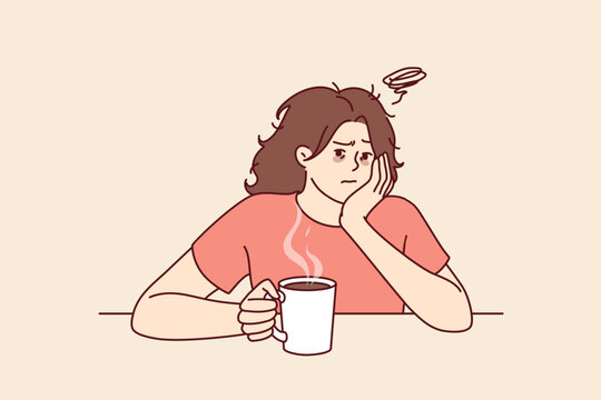 Tired woman with sad face drinks hot coffee and does not want to go to work due to lack of sleep. Upset girl is sitting at table with mug of coffee on Monday morning and is sad because weekend is over
