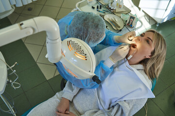 top view of a dentist treating teeth to a young woman in a dental chair