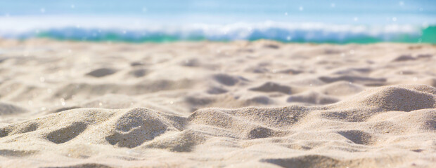 Abstract blur defocused background, nature of tropical summer beach with rays of sun light. Golden sand beach, sea water against blue sky with white clouds. Copy space, summer vacation concept.