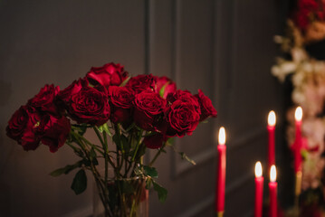Luxury candlelight dinner setup for couple on Valentine's day. Romantic date. Setting table in restaurant. Location decoration red flowers, decor candles for surprise marriage proposal. Closeup detail