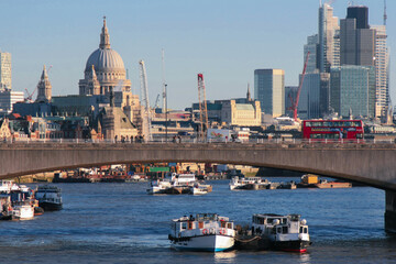 Obraz na płótnie Canvas The Thames river in London with a bridge, boats and the skyline of London with skyscrapers and St. Paul’s Cathedral in the background