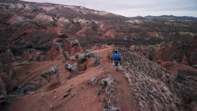 Aerial View of Female Caucasian Tourist Walking Among Fairy Chimneys in Imaginary valley, Devrent Cappadocia, Turkey