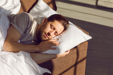 Young man is still asleep. Relaxed handsome bearded young man in a T shirt is sleeping on a soft...