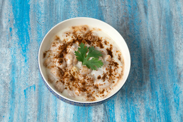 Dahi vada or bhalla is a type of chaat originating from the Indian and popular throughout South Asia. Dahi bhalla bowl on textured background. 