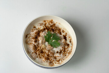 Dahi vada or bhalla is a type of chaat originating from the Indian and popular throughout South Asia. Dahi Bhalla bowl on white background.