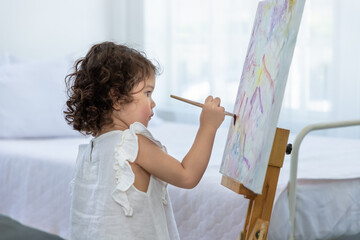 Cute young preschool Caucasian child girl enjoy drawing with watercolor on canvas.