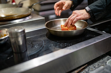man chef cooking fried tuna fish in frying pan on kitchen