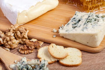 Healthy food. Differet type of cheese, honey and nuts on wooden background.