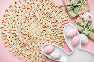 plate rabbit, easter eggs, gifts with green ribbon, spring sakura flowers on a pastel pink background. delicate Easter composition. copy space. view from above. flat lay