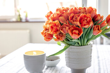 Spring composition with a bouquet of orange tulips in the interior of the house.