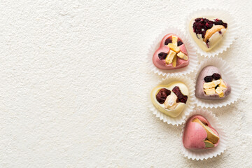 chocolate sweets in the form of a heart with fruits and nuts on a colored background. top view with space for text, holiday concept