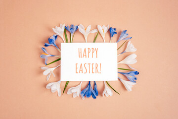 Card with words Happy Easter and frame of crocus flowers on neutral background. Top view, flat lay