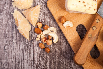 Different type of cheese and nuts on wooden background in close up photo. Copyspace available