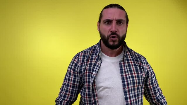 Angry mid adult bearded man scolding looking at camera isolated on yellow background. Portrait annoyed male person talks emotionally, rebuking blaming yelling shouting sb displeased for fault or wrong