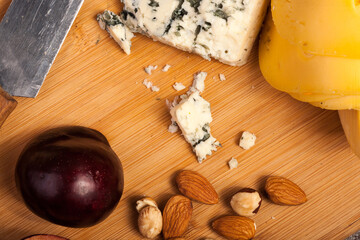 Nuts, cheese and fruits on wooden background in studio photo