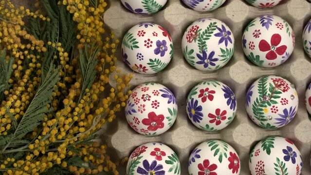 Colorful Easter eggs and mimosa flowers rotation. Easter holiday concept. Easter egg is traditional symbol for religious holiday. Christian celebration traditions, flat lay top view slow motion