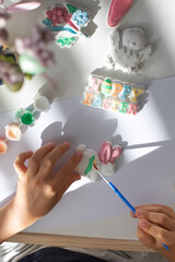 A child paints an Easter bunny figurine. Easter children's crafts.