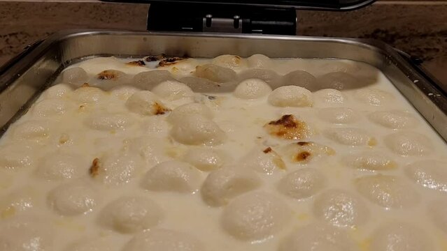 Indian Bengali traditional Sweet Rasagulla (cheese balls) soaked in syrup made of milk and sugar, displayed as a dessert in a multicuisine restaurant.