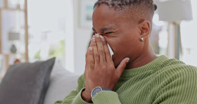 Sick, blowing nose and virus with black man on sofa for covid, fatigue and disease. Allergies, sneezing and tired with male and tissue in living room at home for problem, hayfever and sinusitis