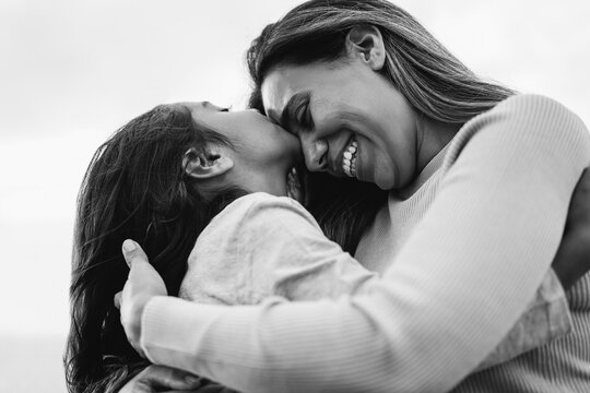 Happy latin mother and daughter having tender moment together outdoor - Main focus on mom mouth