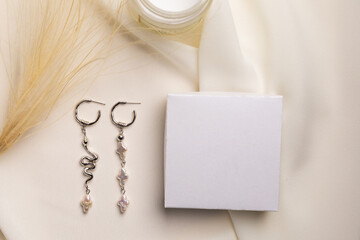 Fototapeta na wymiar Elegant jewelry set of silver earrings with gem and gift box mock up copy space. Jewelry set minimalist style. Handmade bijouterie concept.
