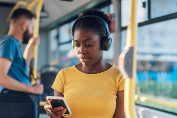 African american woman riding in a bus and using a smartphone