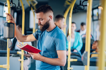 Man reading a book while riding in a bus