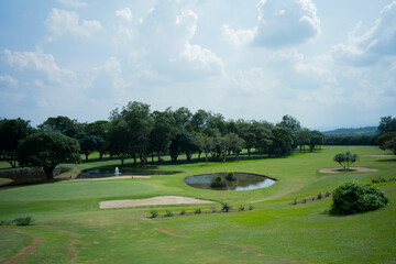 Wide shot of a golf course with a sand trap and water hazard.