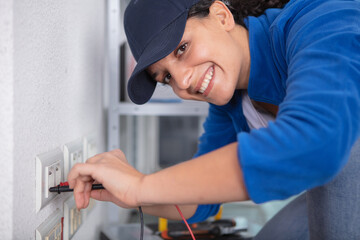 young brunette woman repairs an electric socket