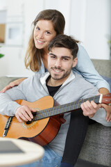 romantic young man playing the guitar to his beloved girl