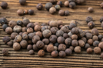 Allspice spice on dark rustic wooden background.