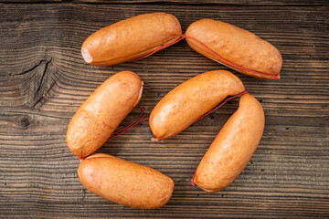 Smoked sausages on dark rustic wooden background.