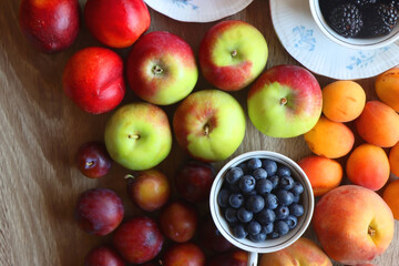 Berries in vintage porcelain dishes, other healthy fruit and vegetable on wooden table. Top view.