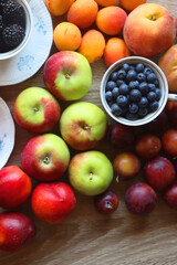 Berries in vintage porcelain dishes, other healthy fruit and vegetable on wooden table. Top view.