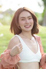 Fototapeta premium Woman smiling with perfect smile and white teeth in a park and looking at camera, Portrait of beautiful woman smiling and looking away at park during sunset. Happy cheerful girl laughing closeup.