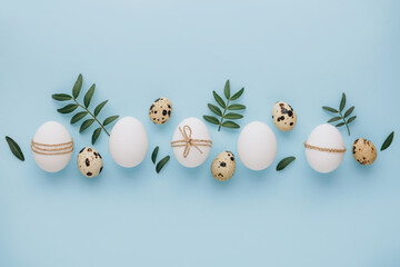 Composition with Easter eggs and flower blossom on blue background. Minimal easter concept.