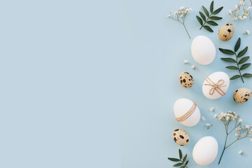 Composition with Easter eggs and flower blossom on blue background. Minimal easter concept.